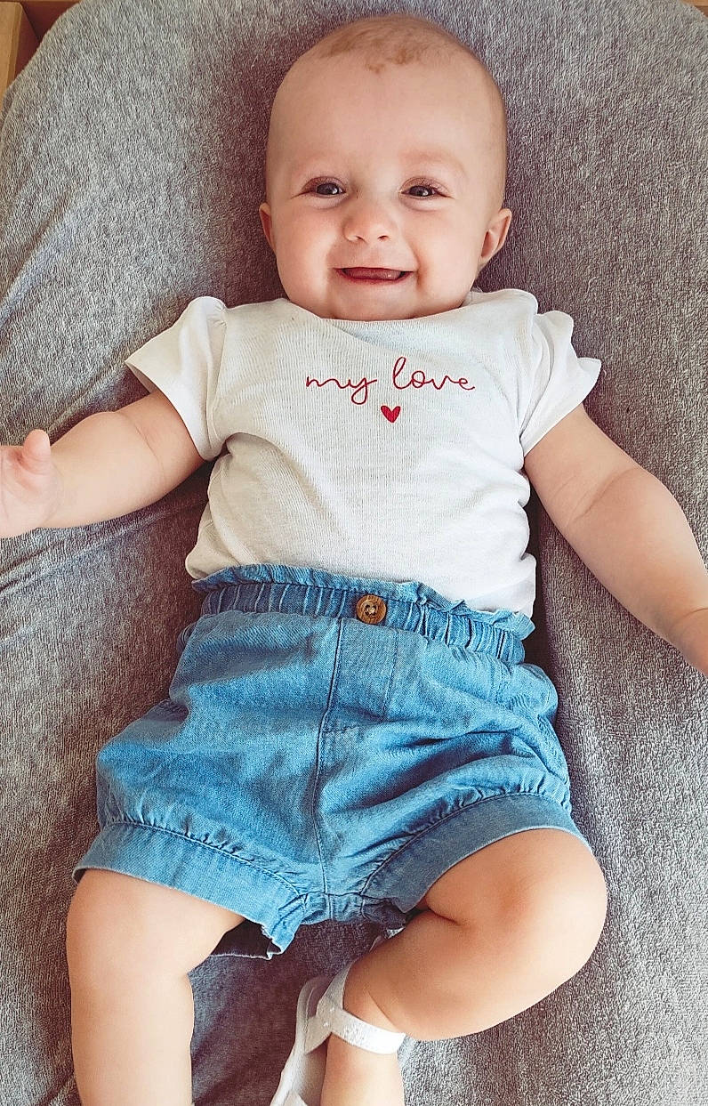 Anaë participe au concours pour gagner de l'argent avec cette photo : azure, baby, baby_toddler_clothing, cheek, chin, eye, face, finger, head, human_body, iris, joy, neck, person, pink, shoulder, skin, sleeve, smile, stomach