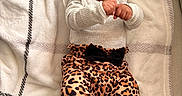 Myla joined the competition — help win amazing prizes! baby, infant, smiling, happy, lying_down, blanket, pacifier, leopard_print, clothing, cute, child, indoors, cozy, portrait, person, toddler, soft_texture, black_bow, patterned_pants, playful