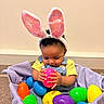 Myla joined the competition — help win amazing prizes! baby, child, bunny_ears, easter_eggs, basket, colorful, yellow_shirt, denim_overalls, indoor, curious, playful, toys, floor, purple_blanket, cute, infant, hands, smiling, holiday, celebration