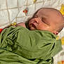 baby, newborn, infant, sleeping, swaddle, blanket, green_cloth, face, cheek, head, ear, portrait, closeup, soft_texture, fabric, nursery, indoors, peaceful, cute, calm