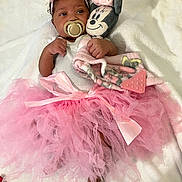 Kehlani joined the competition — help win amazing prizes! baby, infant, tutu, pink, headband, flower, pacifier, plush_toy, minnie_mouse, blanket, soft, cute, foot, hand, person, lying_down, clothing, child, indoor, portrait