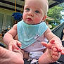 baby, infant, blue_eyes, bib, onesie, barefoot, outdoor, patio, swing, greenery, curious, close_up, child, person, cute, summer, daylight, skin, foot, hand