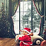 Fayver participe au concours pour gagner de l'argent avec cette photo : baby, child, christmas_tree, curtains, cute, decorations, festive, holiday, holiday_decor, indoor, person, santa_claus_costume, seasonal, smiling, snow, toy, toy_car, window, winter, wooden_floor