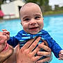 baby, child, smiling, swimsuit, striped_clothing, water, pool, adult_hand, outdoor, happy, face, skin, holding, closeup, summer, recreation, playful, parent, head, person