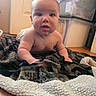 baby, infant, blanket, floor, indoor, person, face, head, eyes, mouth, skin, storage_box, door, wood_floor, curious, child, young, crawling, cozy, home