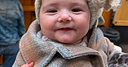 Ava a rejoint le concours — aidez-le/la à gagner de superbes lots ! baby, child, smile, hat, coat, hand, red_nail_polish, plaid, fuzzy, indoor, person, blurred_background, face, cute, warm_clothing, portrait, holding, infant, happy, cozy