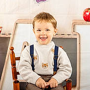 Aaron a rejoint le concours — aidez-le/la à gagner de superbes lots ! child, boy, smiling, sweater, suspenders, chair, apples, pencils, wooden_chair, backdrop, letters, abc, cute, happy, portrait, indoor, clothing, face, person, brown_hair