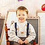 child, boy, smiling, sweater, suspenders, chair, apples, pencils, wooden_chair, backdrop, letters, abc, cute, happy, portrait, indoor, clothing, face, person, brown_hair