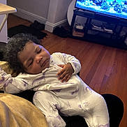 Mylanii joined the competition — help win amazing prizes! aquarium, baby, blanket, child, cozy, curly_hair, cute, furniture, hand, home, indoor, living_room, onesie, peaceful, person, relaxation, resting, sleeping, television, wooden_floor