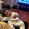 aquarium, baby, blanket, child, cozy, curly_hair, cute, furniture, hand, home, indoor, living_room, onesie, peaceful, person, relaxation, resting, sleeping, television, wooden_floor
