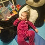 baby, plush_toy, panda, onesie, child, snack, toy, indoor, floor_mat, diapers, colorful, curly_hair, relaxed, cute, infant, play_area, stuffed_animal, childcare, soft_toys, home