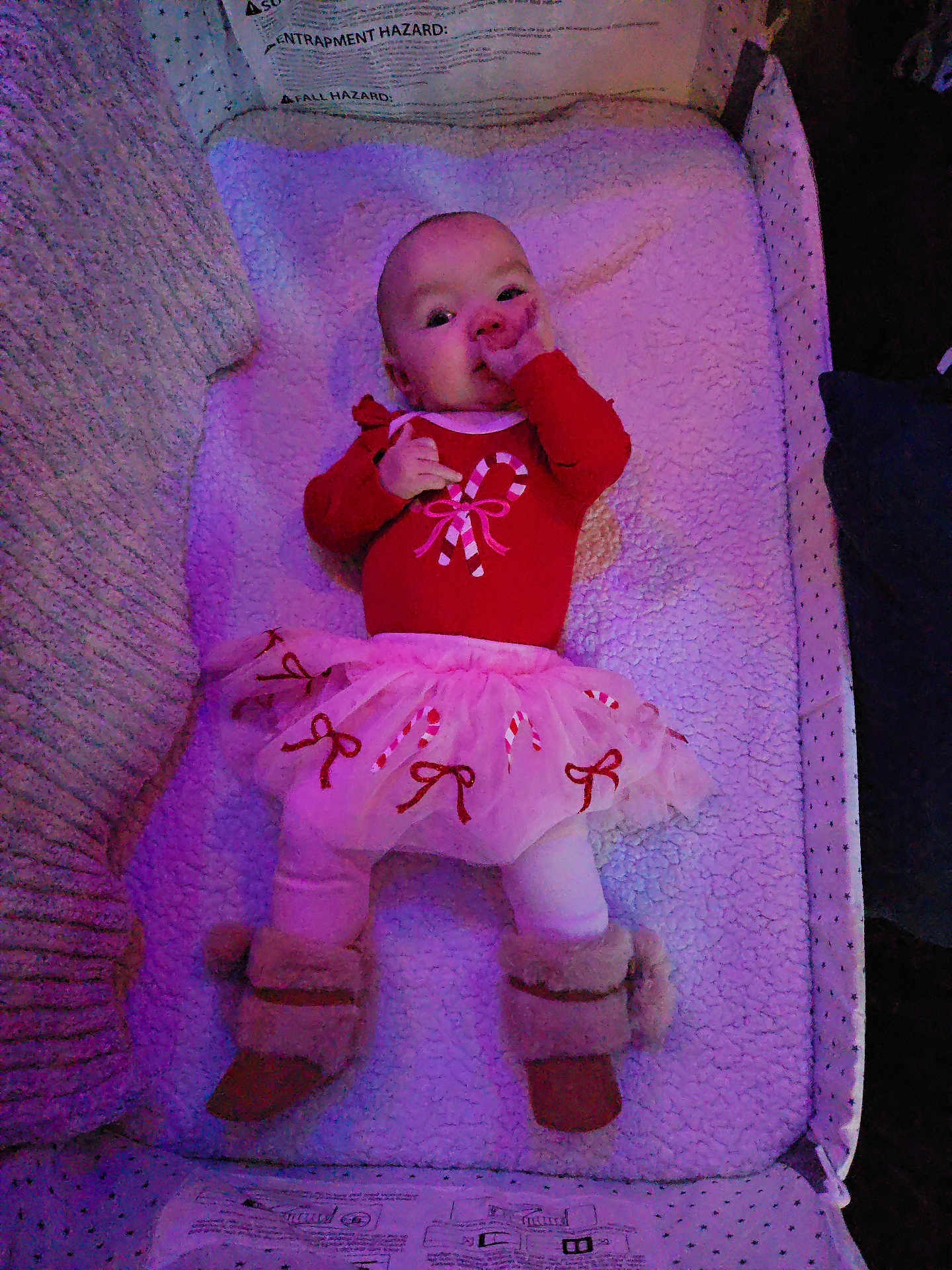 Penelope is registered to the contest to win money with this photo: baby, infant, lying_down, blanket, red_clothing, pink_tutu, boots, fur_boots, candy_cane, holiday_theme, cute, indoors, soft_texture, cozy, child, toddler, sucking_thumb, smiling, face, person