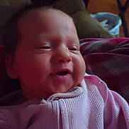 Alisa is registered to the contest to win money with this photo: baby, infant, smiling, face, person, indoor, couch, clothing, pink, sweater, table, furniture, home, relaxing, child, portrait, young, cozy, comfort, seated