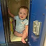 baby, child, locker, books, blue, striped_shirt, indoor, floor, smile, tongue_out, cute, sitting, person, furniture, storage, metal, happy, playful, small_space, curious
