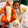baby, child, plush_toy, tigger, winnie_the_pooh, pajamas, blanket, bed, indoor, cute, infant, stuffed_animal, soft_toy, childrens_clothing, face, person, home, comfort, sleepwear, furniture