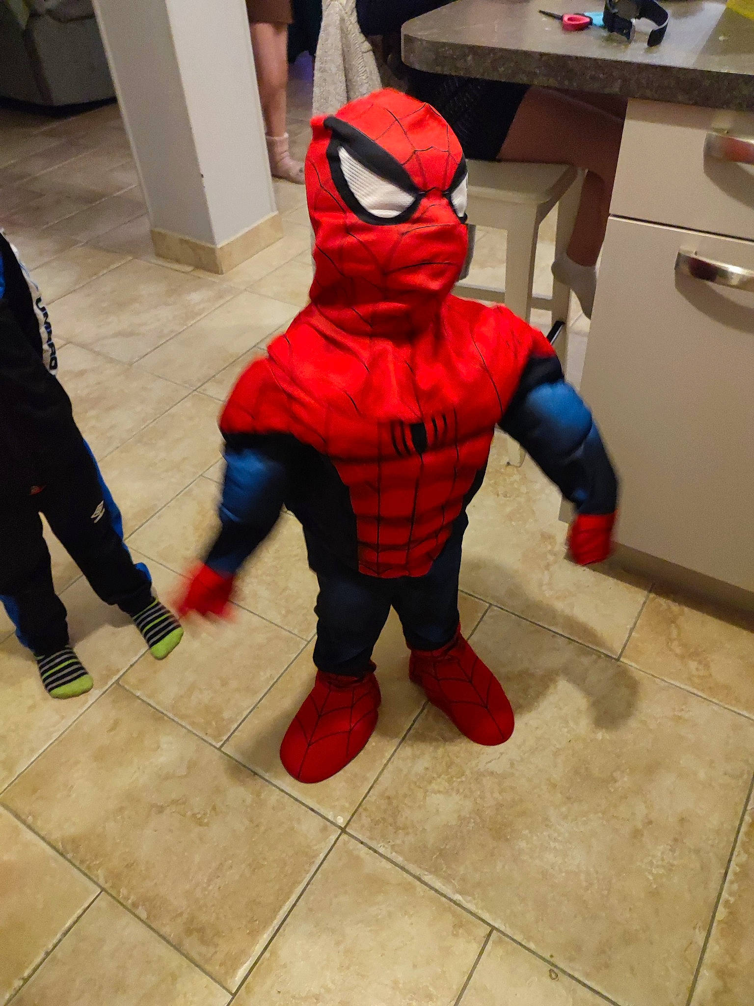 Sohann participe au concours pour gagner de l'argent avec cette photo : carmine, child, computer_keyboard, costume, desk, drawer, fictional_character, floor, flooring, fur, hat, human_leg, mascot, person, personal_protective_equipment, shoe, sleeve, spider_man, stuffed_toy, table