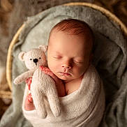 Robin a rejoint le concours — aidez-le/la à gagner de superbes lots ! newborn, baby, sleeping, teddy_bear, knitted_toy, blanket, soft_texture, wrapped, cozy, cute, infant, portrait, peaceful, warm_tones, closeup, child, cocooned, resting, indoors, baby_bedding