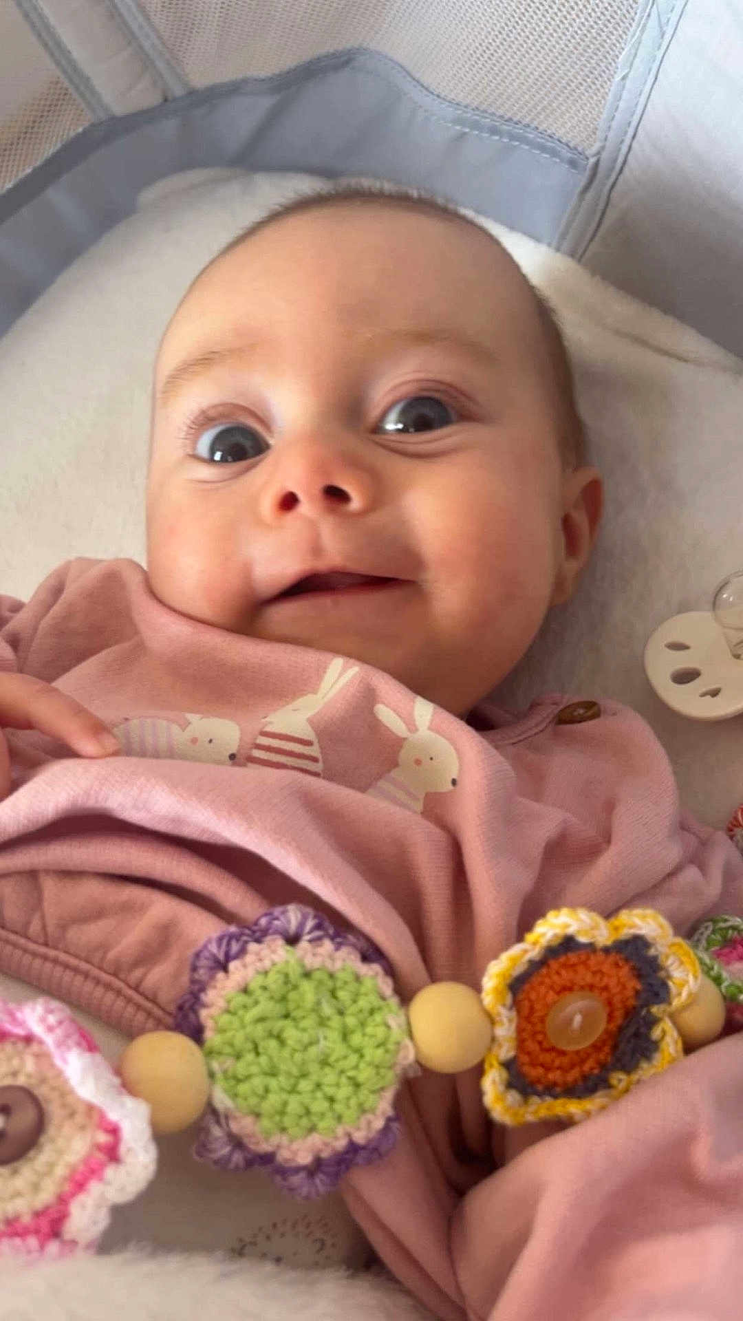 Ariana participe au concours pour gagner de l'argent avec cette photo : baby, infant, smiling, wide_eyes, onesie, bunny_print, pacifier, pacifier_clip, crochet_toy, wooden_beads, close_up, portrait, lying_down, blanket, nursery, cute, cheeks, adorable, soft_texture, clothing