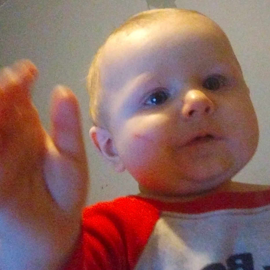 Jerimiah joined the competition — help win amazing prizes! adult_partial, baby, background, casual_clothing, child, closeup, curious, expression, face, hand, indoor, person, photography, portrait, reaching, red_shirt, room, skin, white_shirt, young_child