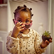 Meylie participe au concours pour gagner de l'argent avec cette photo : child, cozy, curious, curly_hair, cute, decor, expression, face, furniture, hand, heart_shaped, indoor, patterned_clothing, plant, portrait, pot, small_plant, sunglasses, sweater, young_child