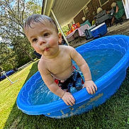 Axel is registered to the contest to win money with this photo: toddler, child, water, pool, blue_pool, grass, outdoor, summer, wet_hair, bare_chest, shorts, backyard, people, adults, chairs, cooler, table, trees, sunny, daytime