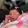 newborn, baby, infant, sleeping, face, hand, eye_rubbing, hair_bow, blanket, pink, purple, cozy, portrait, close_up, indoors, cuddled, peaceful, resting, soft, photography