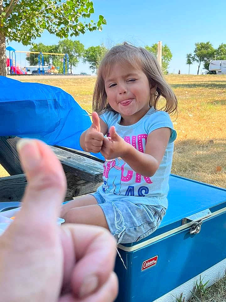 Gracelynn is registered to the contest to win money with this photo: automotive_exterior, bumper, finger, fun, grass, hand, happy, joy, lap, leg, leisure, motor_vehicle, person, plant, recreation, sky, smile, summer, thumb, toddler