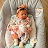 baby, newborn, infant, child, portrait, sitting, baby_seat, headband, bow, blanket, stuffed_animal, bunny, pacifier, floral_clothing, pink, cushion, indoor, wood_floor, face, cute