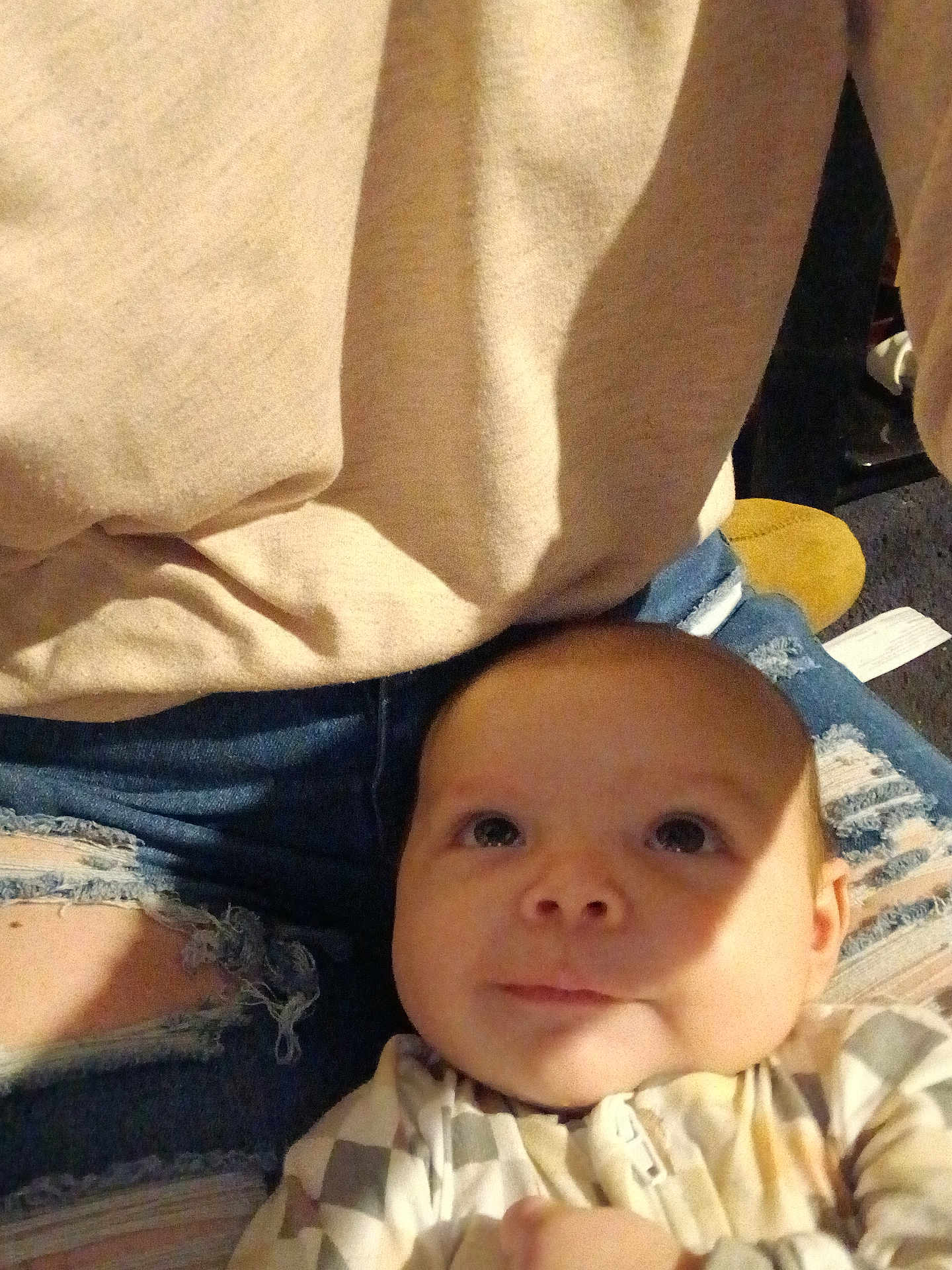 Kason is registered to the contest to win money with this photo: baby, infant, person, clothing, jeans, ripped_jeans, lap, looking_up, casual, indoor, soft_lighting, shadow, face, head, young_child, cute, portrait, relaxed, seated, human