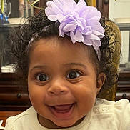 Haliey is registered to the contest to win money with this photo: adorable, apparel, baby, baby_girl, cheerful, child, closeup, curly_hair, cute, face, flower, happy, headband, indoors, infant, joy, person, portrait, smiling, white_clothing