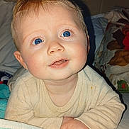 Ethan participe au concours pour gagner de l'argent avec cette photo : baby, infant, blue_eyes, smiling, face, portrait, close_up, bedroom, blanket, bedding, onesie, hands, cheeks, soft_skin, plush, cute, lying_down, young_child, expression, eyelashes