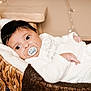 baby, big_eyes, binky, blanket, calm, cozy, cute, dark_hair, hand, indoor, infant, knitted_throw, lying_down, newborn, pacifier, portrait, soft_texture, white_clothing, wicker_basket, wooden_table