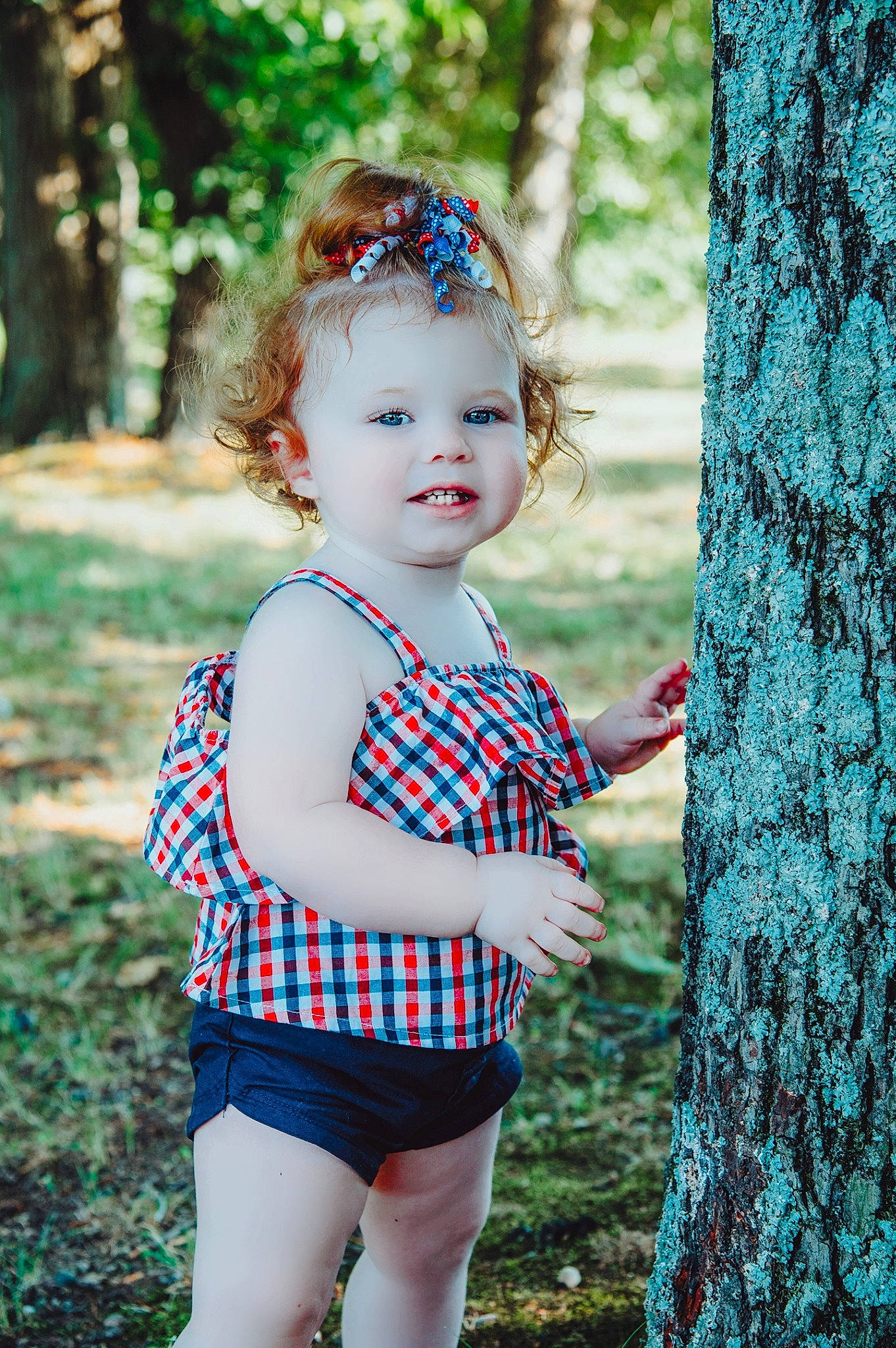 Enola joined the competition — help win amazing prizes! baby, baby_toddler_clothing, child, grass, happy, leaf, people_in_nature, person, photograph, pink, plant, shorts, smile, standing, summer, sunlight, tartan, toddler, tree, wood