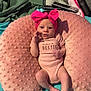 baby, infant, pink_bow, onesie, pillow, blanket, remote_control, baby_girl, soft_texture, cute, indoor, portrait, newborn, cozy, headwear, laying_down, small_hands, curious, child, comfortable