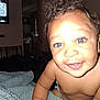 baby, child, smiling, blue_eyes, curly_hair, blanket, indoor, close_up, face, skin, arm, diaper, furniture, television, qr_code, happy, cute, infant, person, portrait