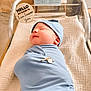 newborn, baby, swaddle, blue, hat, sleeping, bassinet, hospital, blanket, name_tag, infant, peaceful, resting, cute, soft, child, portrait, indoors, person, cozy