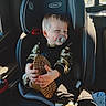 automobile, baby, blond_hair, boots, buckled_in, camouflage_clothing, car_seat, child, hands, indoors, pacifier, portrait, safety_harness, shoe_sole, sitting, smiling, sunlight, toddler, vehicle, window