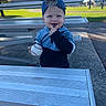 Sawyer is registered to the contest to win money with this photo: child, toddler, smiling, baseball, baseball_fan, sports, ball, cap, blue_clothing, outdoor, bleachers, stadium, park, sunlight, portrait, sitting, happy, face, grass, playful