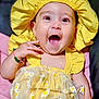 baby, child, yellow_clothing, bonnet, smiling, happy, tutu, floral_pattern, cute, infant, portrait, sitting, bracelet, hand, face, bright_colors, cheerful, cute_outfit, closeup, adorable