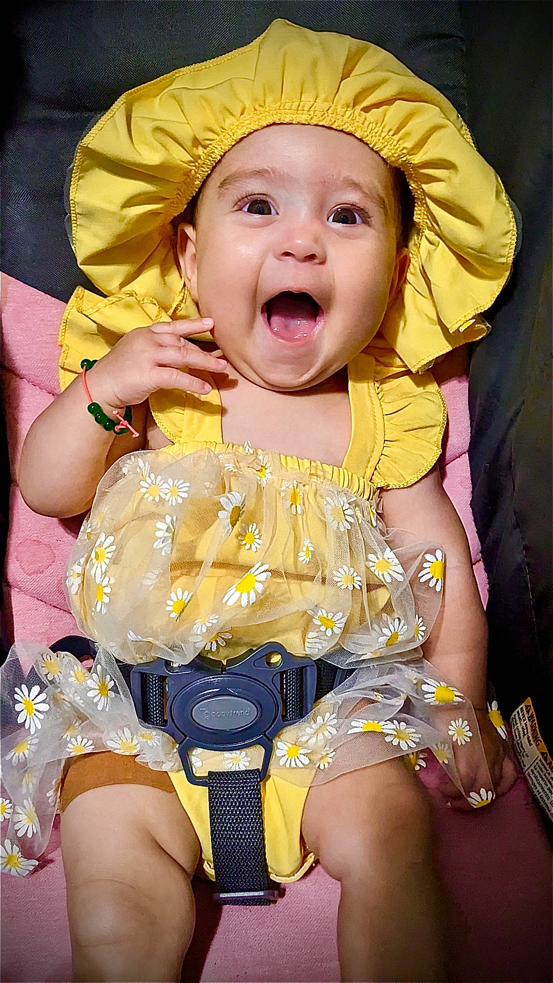 Serenity is registered to the contest to win money with this photo: accessory, baby, baby_bracelet, car_seat, child, clothing, cute, daisies, expression, face, happy, indoors, infant, portrait, seatbelt, sitting, smiling, toddler, yellow_dress, yellow_hat
