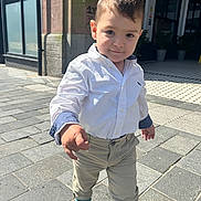 Eduardo joined the competition — help win amazing prizes! toddler, child, boy, street, urban, sidewalk, pavement, white_shirt, khaki_pants, blue_shoes, confident, sunny, daylight, walking, building, window, casual_clothing, pose, smile, person