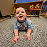 baby, blue_shirt, carpet, child, clothing, crawling, cute, face, floor, hands, happy, home, indoor, infant, person, playroom, room, smiling, toy_shelf, wooden_shelf