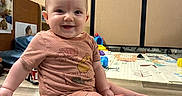 Vernon is registered to the contest to win money with this photo: baby, child, smiling, sitting, floor, indoor, toy, playmat, clothing, person, cute, happy, infant, wooden_floor, room, casual, young_child, expression, toddler, portrait