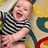 baby, blanket, bright_colors, candid, casual, cheerful, child, colorful_rug, cute, happy, indoors, infant, lying_down, patterned_rug, person, playful, small_hands, smiling, striped_clothing, young_child