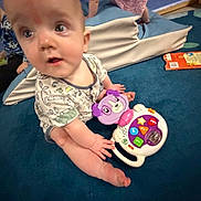 Vernon is registered to the contest to win money with this photo: baby, child, toy, purple, carpet, soft_play, blue, clothing, indoor, floor, person, kids, playtime, pink_dress, curious, infant, sitting, hands, feet, background