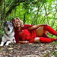 Yuma a rejoint le concours — aidez-le/la à gagner de superbes lots ! woman, dog, forest, red_clothing, cape, boots, greenery, leaves, path, nature, costume, smiling, posing, outdoor, animal, canine, adult, blonde_hair, red_lipstick, friendship