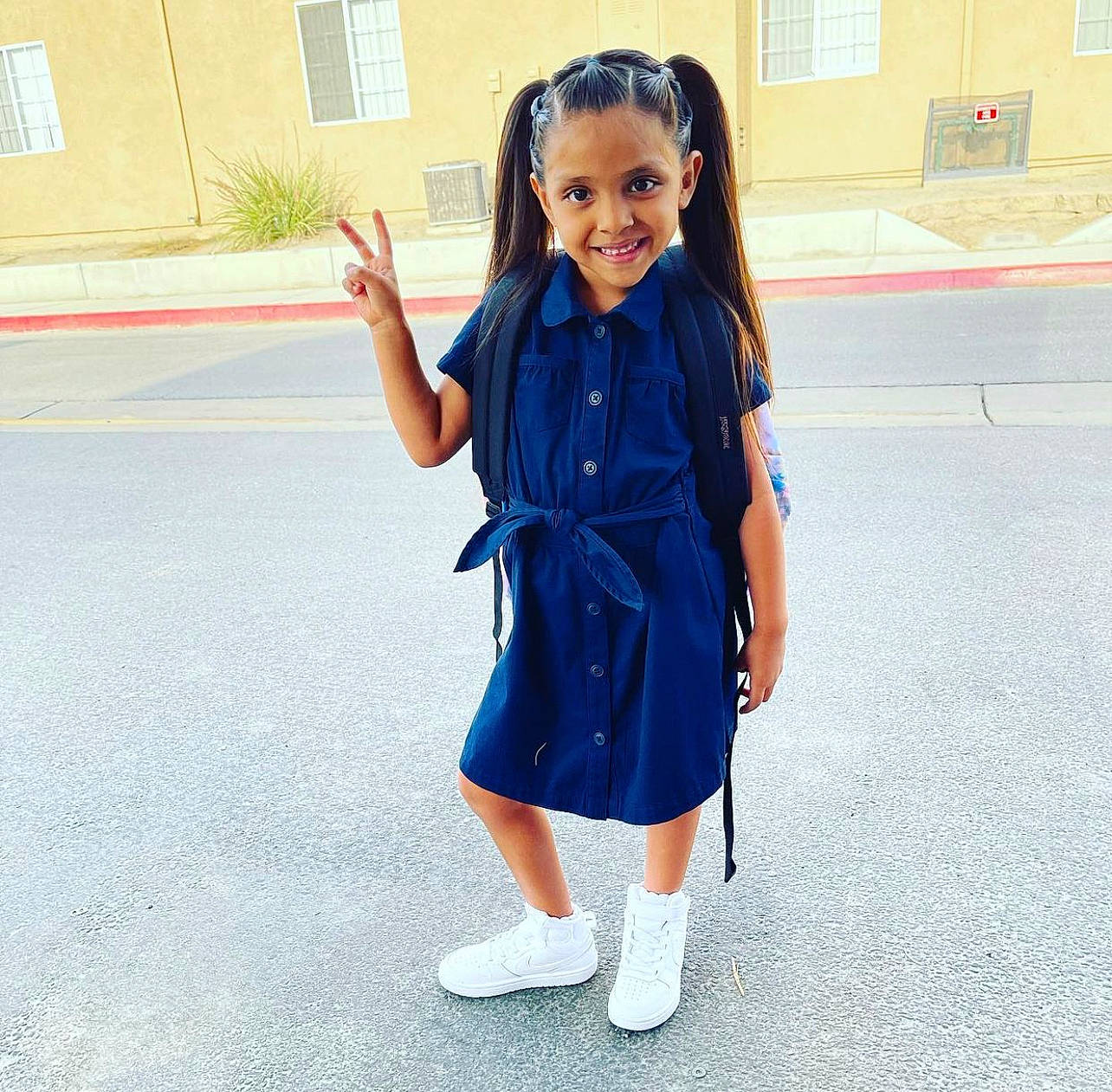 Rosie is registered to the contest to win money with this photo: child, day_dress, denim, electric_blue, fashion_accessory, fun, gesture, happy, human_leg, joy, pattern, person, recreation, school_uniform, sleeve, smile, standing, street_fashion, toddler, uniform