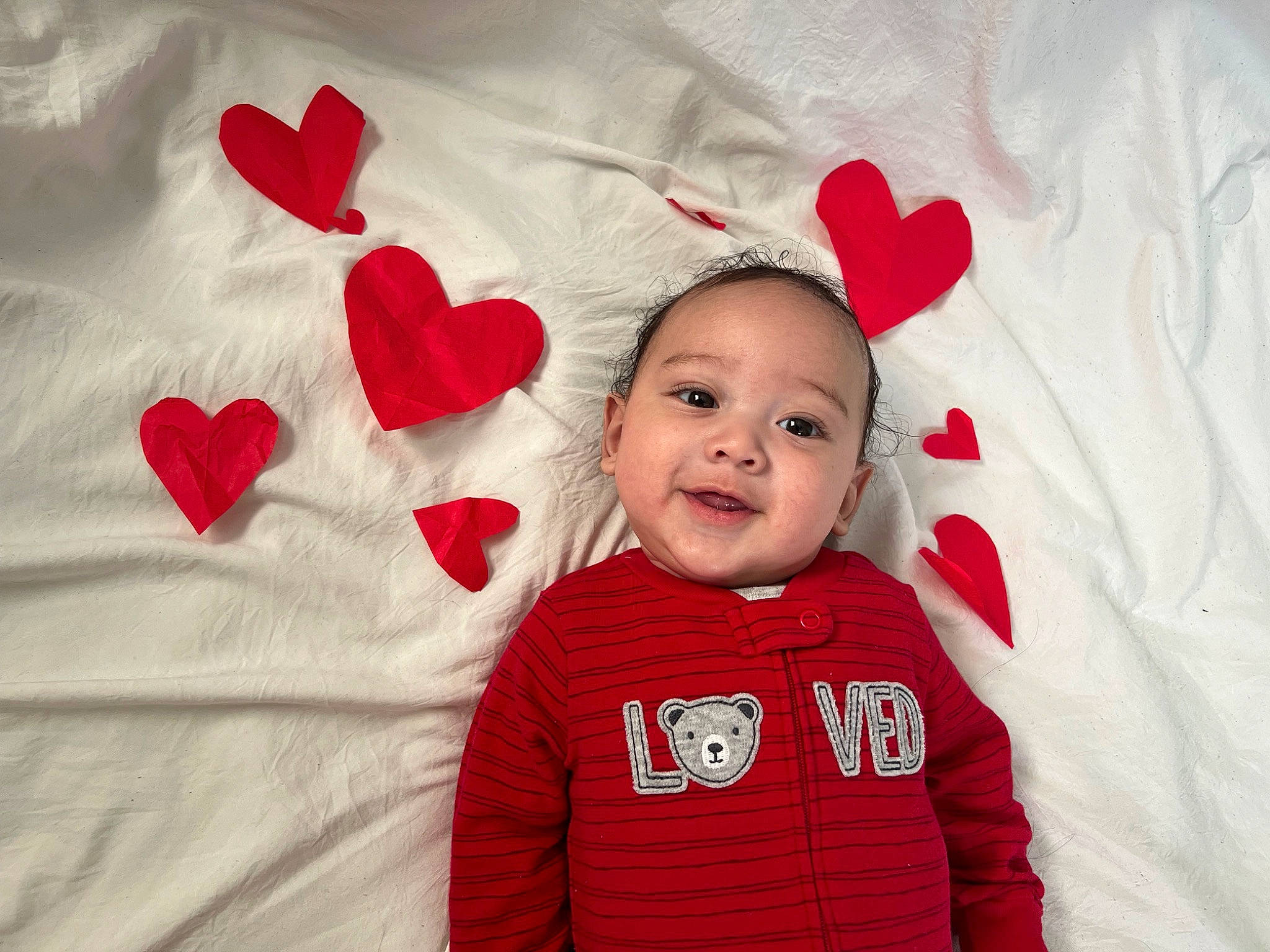 Derrick is registered to the contest to win money with this photo: baby, baby_toddler_clothing, carmine, child, costume_hat, event, fur, happy, holiday, linens, magenta, pattern, person, pink, red, sleeve, smile, t_shirt, textile, toddler