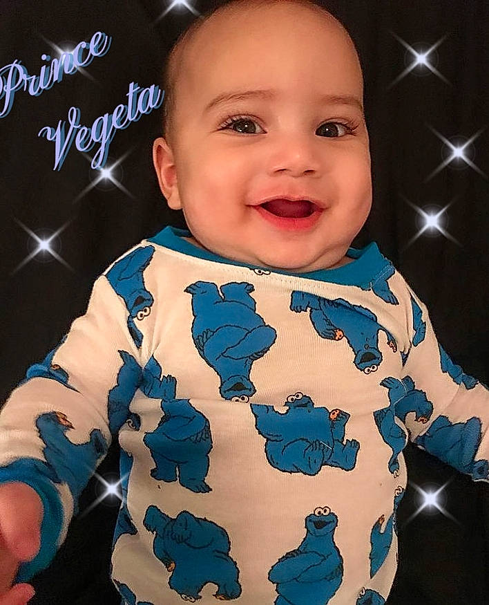 Vegeta is registered to the contest to win money with this photo: baby, baby_toddler_clothing, cheek, child, chin, cool, facial_expression, finger, flash_photography, gesture, hairstyle, happy, joy, outerwear, person, product, sleeve, smile, standing, t_shirt