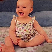 Thais participe au concours pour gagner de l'argent avec cette photo : baby, bed, bedspread, child, cute, floral_outfit, foot, hand, happy, headboard, indoors, infant, pattern, person, portrait, sitting, skin, smiling, toddler, young